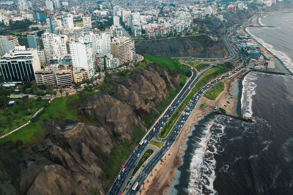 A coastal cityscape with a prominent highway, buildings, and a beach.