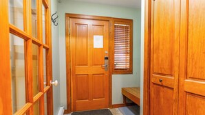 Una puerta de madera con felpudo, un banco y una ventana con persianas.