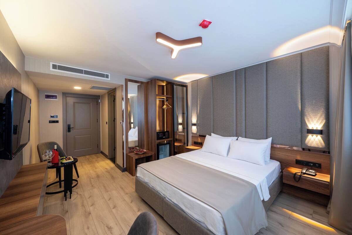 Une chambre d’hôtel moderne, dotée d’un grand lit, de tables de chevet, d’un bureau et d’une chaise.