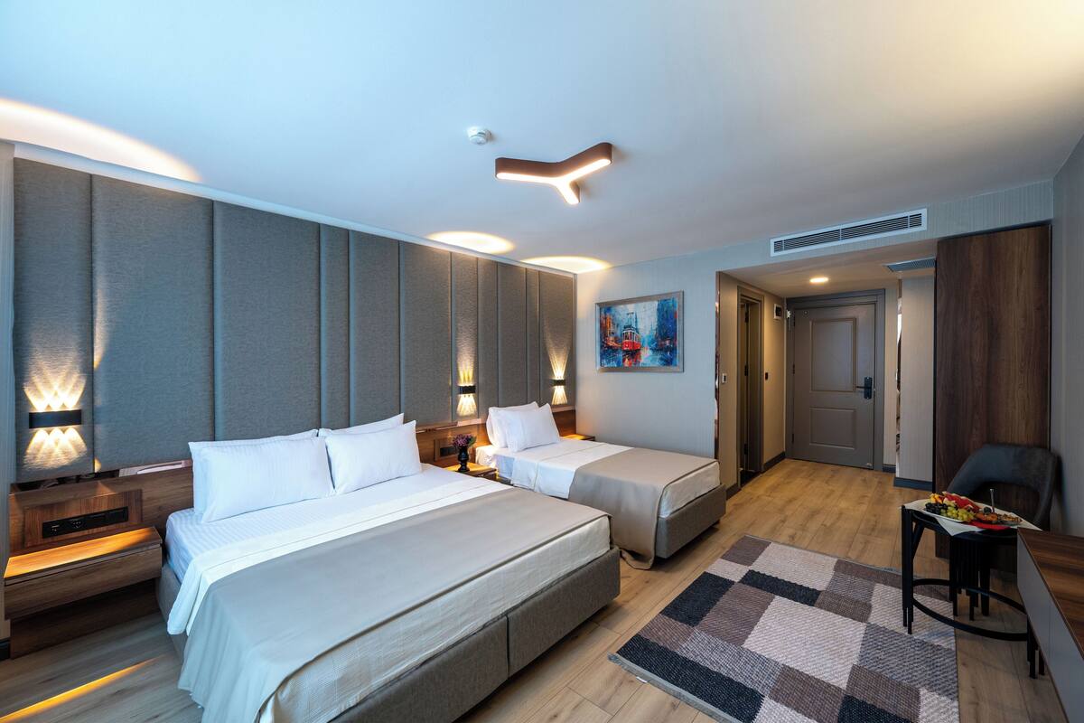 Une chambre d’hôtel avec deux lits, un bureau, une chaise et un tableau au mur.