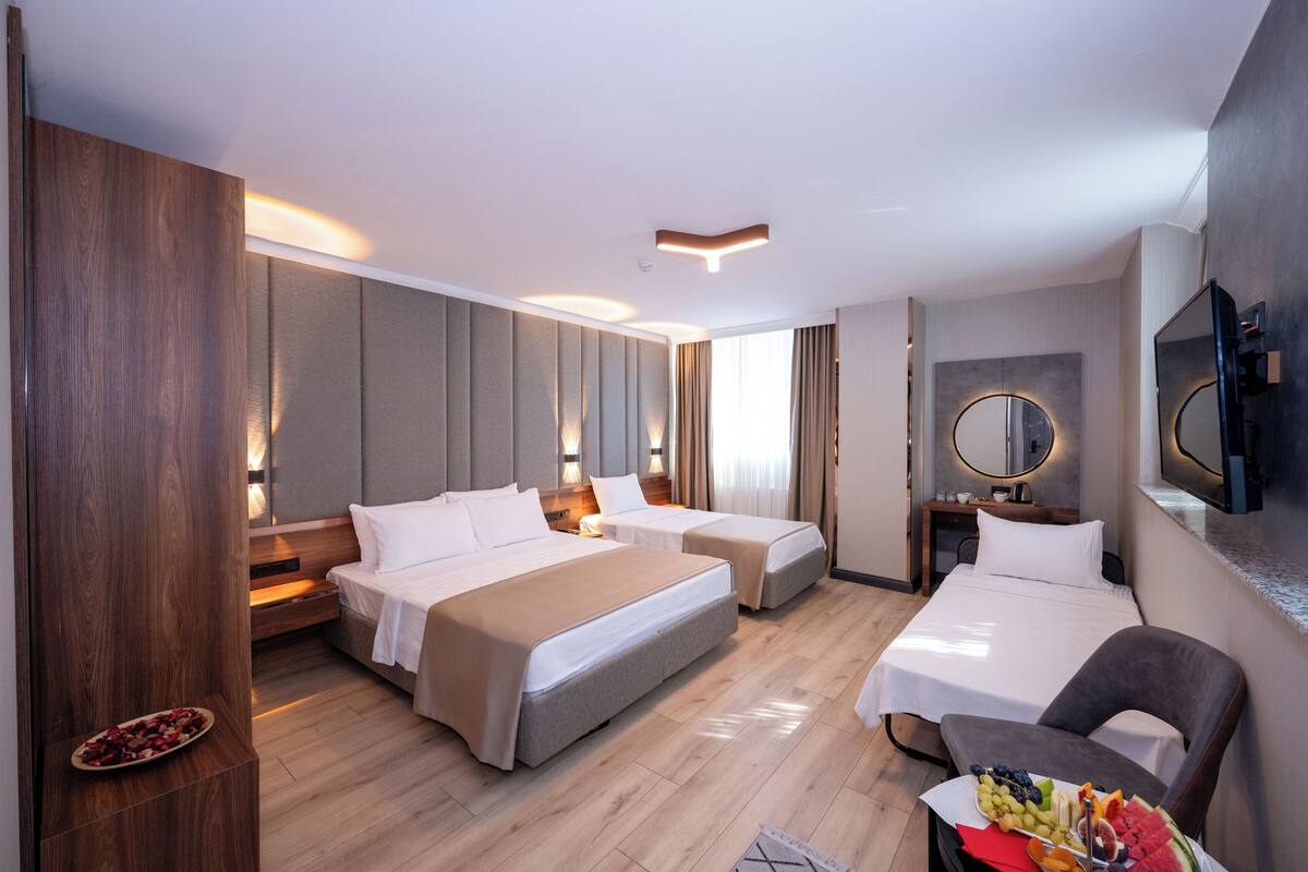 Une chambre d’hôtel avec deux lits, un bureau, une chaise et un téléviseur.