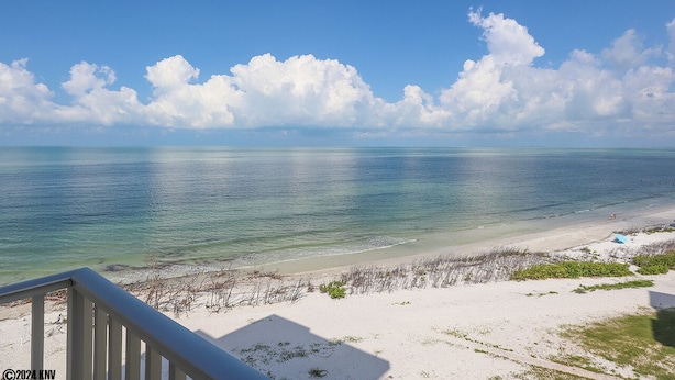 Blick auf einen Strand mit blauem Himmel und ruhigem Wasser.