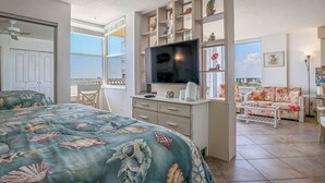 Ein Schlafzimmer mit Bett, Fernseher, Schreibtisch und Meerblick.