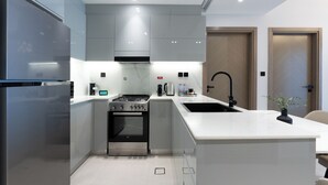 A modern kitchen with a central island, stainless steel appliances, and a built-in oven. - Trendy 2 Bed in Binghatti Canal (Dubai)