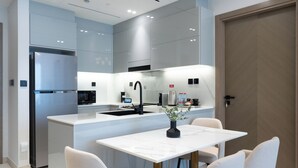 A modern kitchen with a central island, stainless steel appliances, and a dining area with a white table and chairs. - Trendy 2 Bed in Binghatti Canal (Dubai)