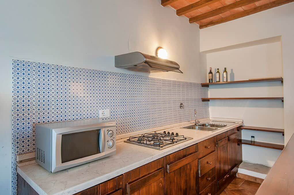 Una cocina con microondas, estufa, lavaplatos y salpicadero decorativo.