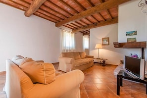 A living room with a wooden ceiling, two sofas, a TV, and a lamp.