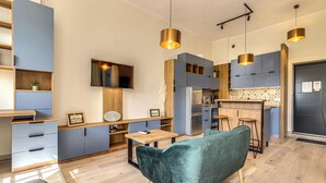 Una cocina moderna con armarios azules, encimera de madera y sofá de terciopelo verde.