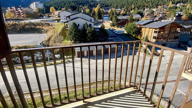 En balkong med utsikt över ett bostadsområde, inklusive hus och en parkeringsplats.