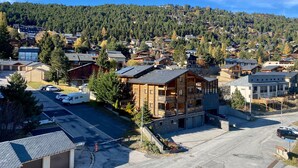 Ett bostadsområde med hus, en parkeringsplats och en skogbeklädd kulle i bakgrunden.