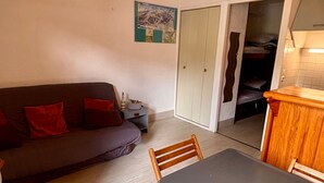 Ett kompakt bostadsutrymme med en soffa, ett matbord och ett köksområde.