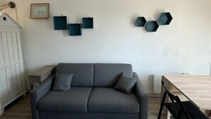 Un salon moderne avec un canapé gris, une table en bois et des œuvres d’art murales de forme hexagonale.