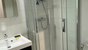 Une salle de bain moderne avec une douche à parois de verre, un lavabo blanc et un miroir.