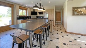 A modern kitchen with a large island, bar stools, pendant lighting, and a view to the outdoors. - Country House with Garden and Spa for 14 in Les Ventes-de-Bourse (Les Ventes-de-Bourse)