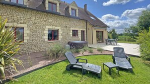 A stone house with a patio area featuring two lounge chairs and a table. - Country House with Garden and Spa for 14 in Les Ventes-de-Bourse (Les Ventes-de-Bourse)