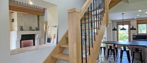 A modern kitchen with a built-in stove, a dining area with bar stools, and a staircase with wooden railings.
