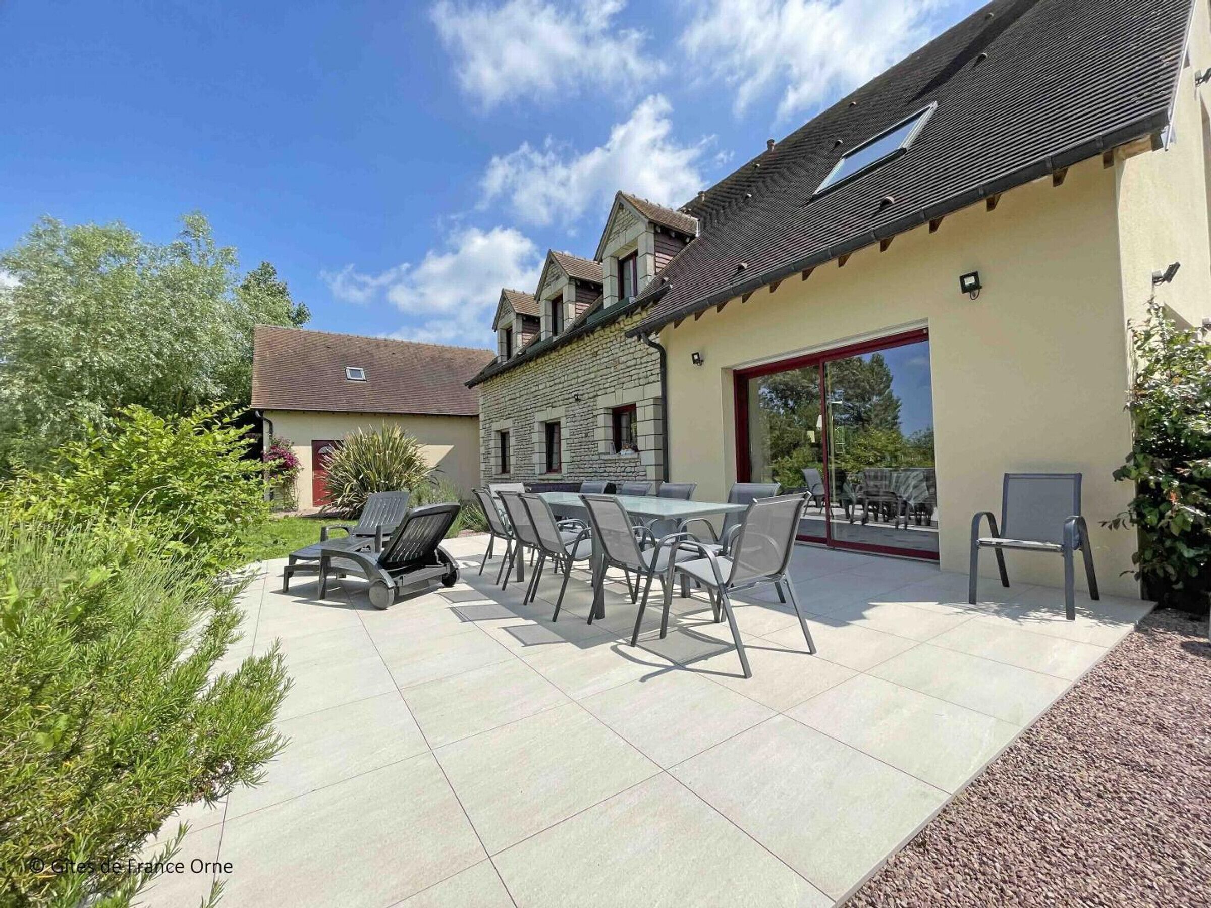 A patio area with a table and chairs, a stone building, and a glass door.