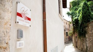 Una calle estrecha con un letrero que dice 'Gelsi Luxury Suites' y un teclado de seguridad en la pared.