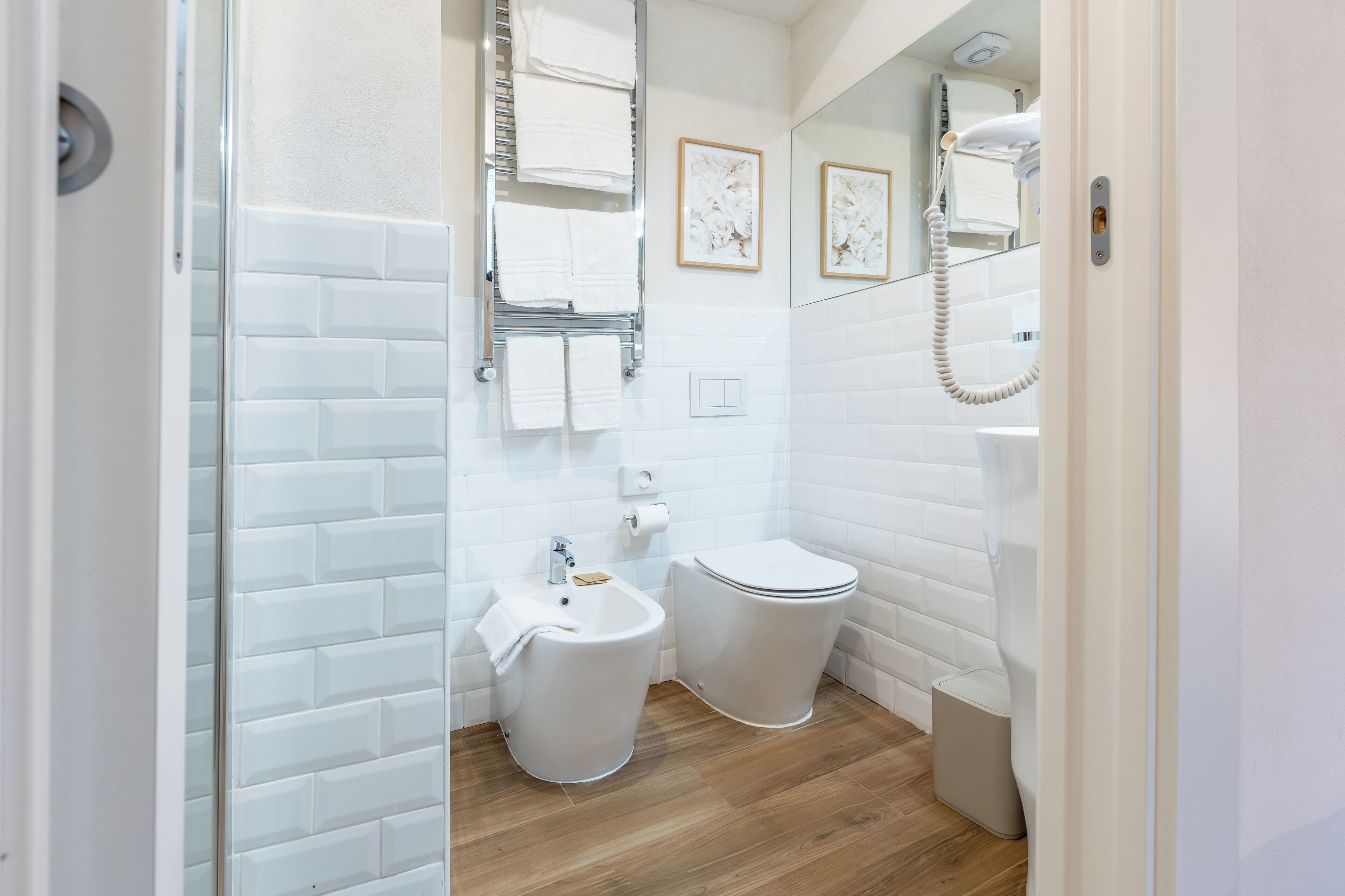 Un baño con azulejos blancos tipo metro, un lavabo, un inodoro y una ducha.