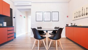 Una cocina moderna con comedor, que cuenta con suelo de madera, sillas negras y muebles de cocina color rojo.
