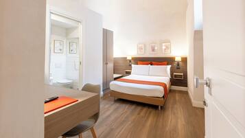 Une chambre d’hôtel avec un lit, une table de chevet, une chaise et une salle de bain visible à travers une porte ouverte.