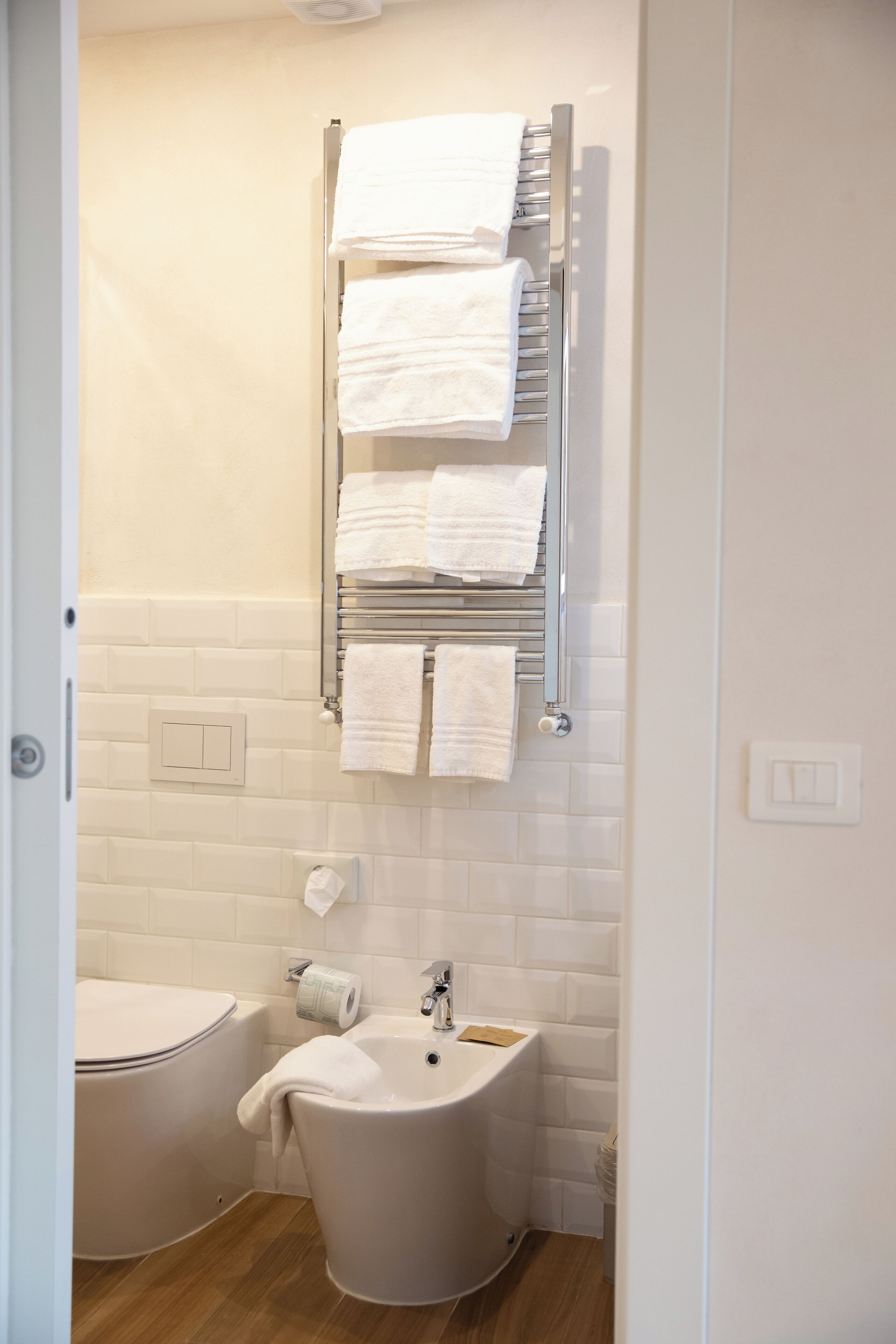 A bathroom with a white bathtub, a sink, and a towel rack with multiple towels.