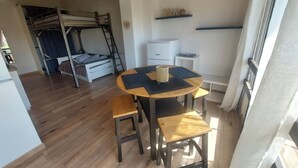 Ein gemütliches Zimmer mit einem Etagenbett, einem kleinen Tisch mit Hocker, einem weißen Schrank und einem Regal mit Dekoration.