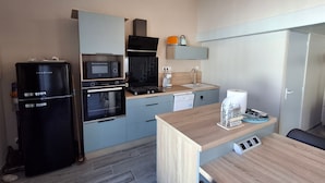 A compact kitchen with a refrigerator, oven, microwave, and a small sink.