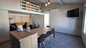 A modern kitchen with a wooden island, black chairs, and a staircase leading to a loft.