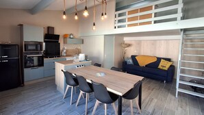 A compact living space with a kitchenette, dining area, and a loft bedroom.