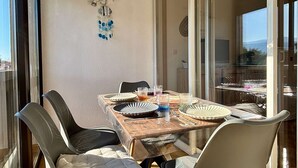 Un comedor con una mesa de madera, cuatro sillas y un separador de vidrio.