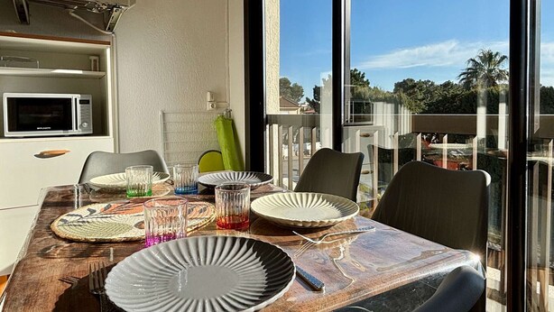 Un comedor con una mesa preparada para dos personas, microondas y vistas al exterior.