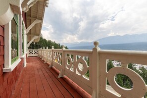 A wooden balcony with a white railing and a view of mountains. - Historic Swiss Chalet Overlooking the Rockies (Golden)