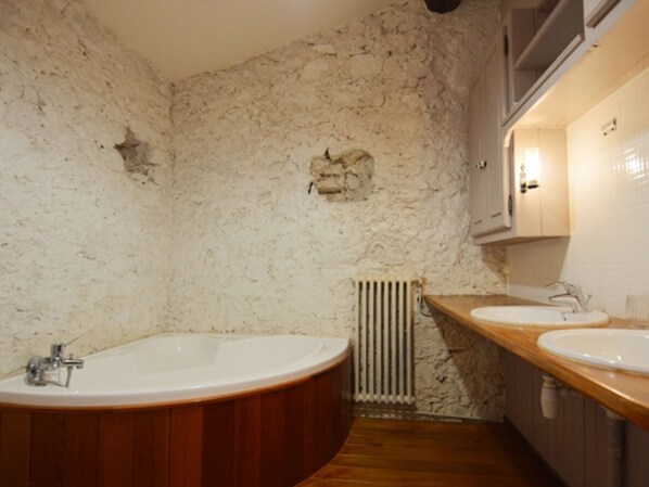 Un baño con una bañera independiente, dos lavamanos y una pared con textura.
