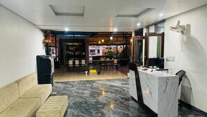 A modern lobby with a marble floor, a reception desk, a sofa, and a dining area with chairs and tables. - Hotel Eagle Inn (Udaipur)