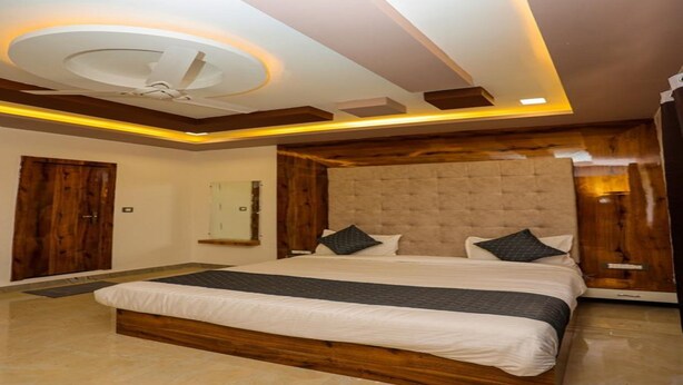 A modern bedroom with a large bed, wooden headboard, and recessed lighting. - Hotel Eagle Inn (Udaipur)