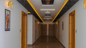 A hallway with wooden doors, recessed lighting, and a marble floor. - Hotel Eagle Inn (Udaipur)