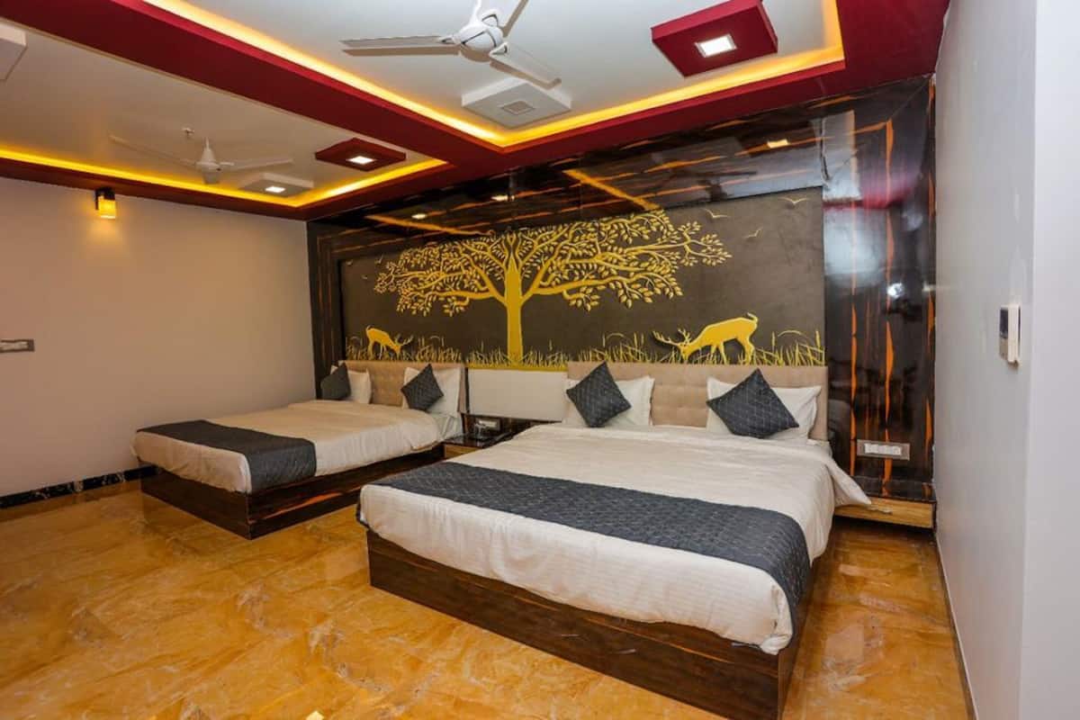 A hotel room with two beds, a ceiling fan, and a mural of a tree and deer.