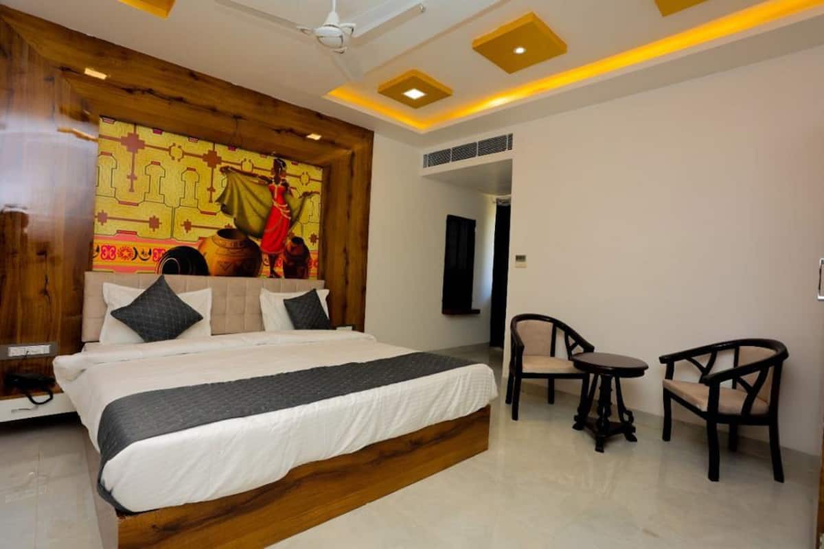 A bedroom with a large bed, a wooden headboard, a small table, two chairs, and a ceiling fan.