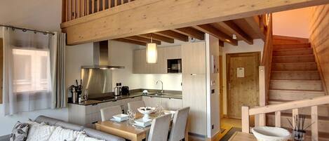Un intérieur moderne comprenant un espace repas, une cuisine et une chambre à coucher située en mezzanine.