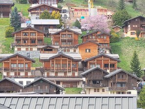 Un conjunto de chalets de madera con balcones, al pie de una ladera.