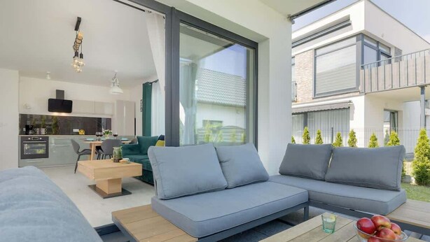 A modern living room with a grey sofa, a wooden coffee table, and a kitchen in the background. - Stylish Apartment in Lukecin | Pool, Terrace, Parking (Lukecin)