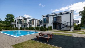 A modern residential building with a swimming pool, a picnic table, and a staircase. - Stylish Apartment in Lukecin | Pool, Terrace, Parking (Lukecin)