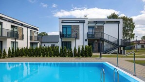 A modern building with a swimming pool, featuring a staircase and a balcony. - Stylish Apartment in Lukecin | Pool, Terrace, Parking (Lukecin)