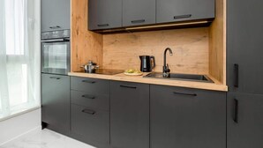 Eine moderne Küche mit dunklen Schränken, einer Holzarbeitsplatte, einem eingebauten Backofen und einem Spülbecken mit Armatur.