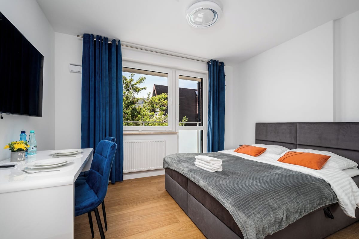 Ein modernes Schlafzimmer mit einem Bett, einem Schreibtisch und einem Fenster mit Vorhängen.