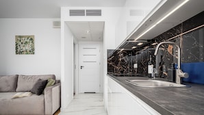 A modern kitchen with a marble countertop, a stainless steel sink, and a blue backsplash. - RentPlanet - Apartament Pileckiego (Warsaw)