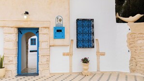 Une entrée d’immeuble avec un arc en pierre, une porte bleue et un pot de fleurs.