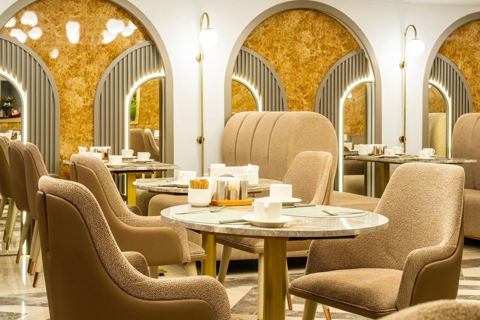 A modern dining area with round tables and upholstered chairs, featuring a warm color palette and elegant lighting.