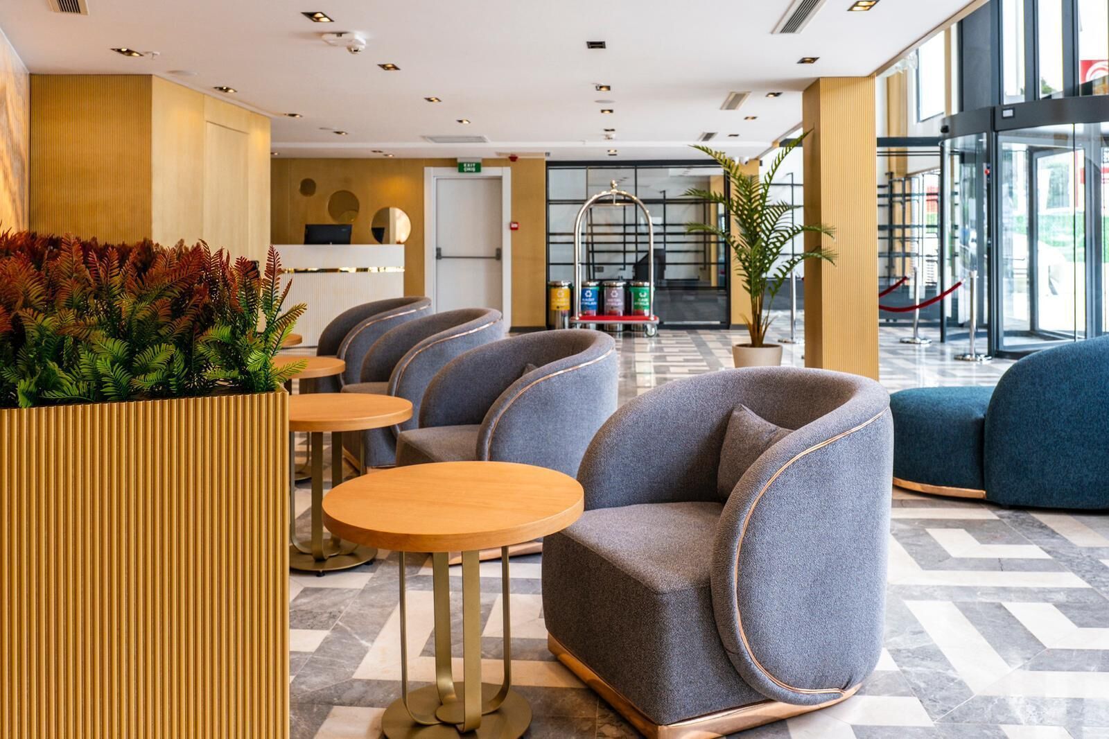 Um lobby moderno com áreas de estar, balcão de recepção e uma grande entrada de vidro.